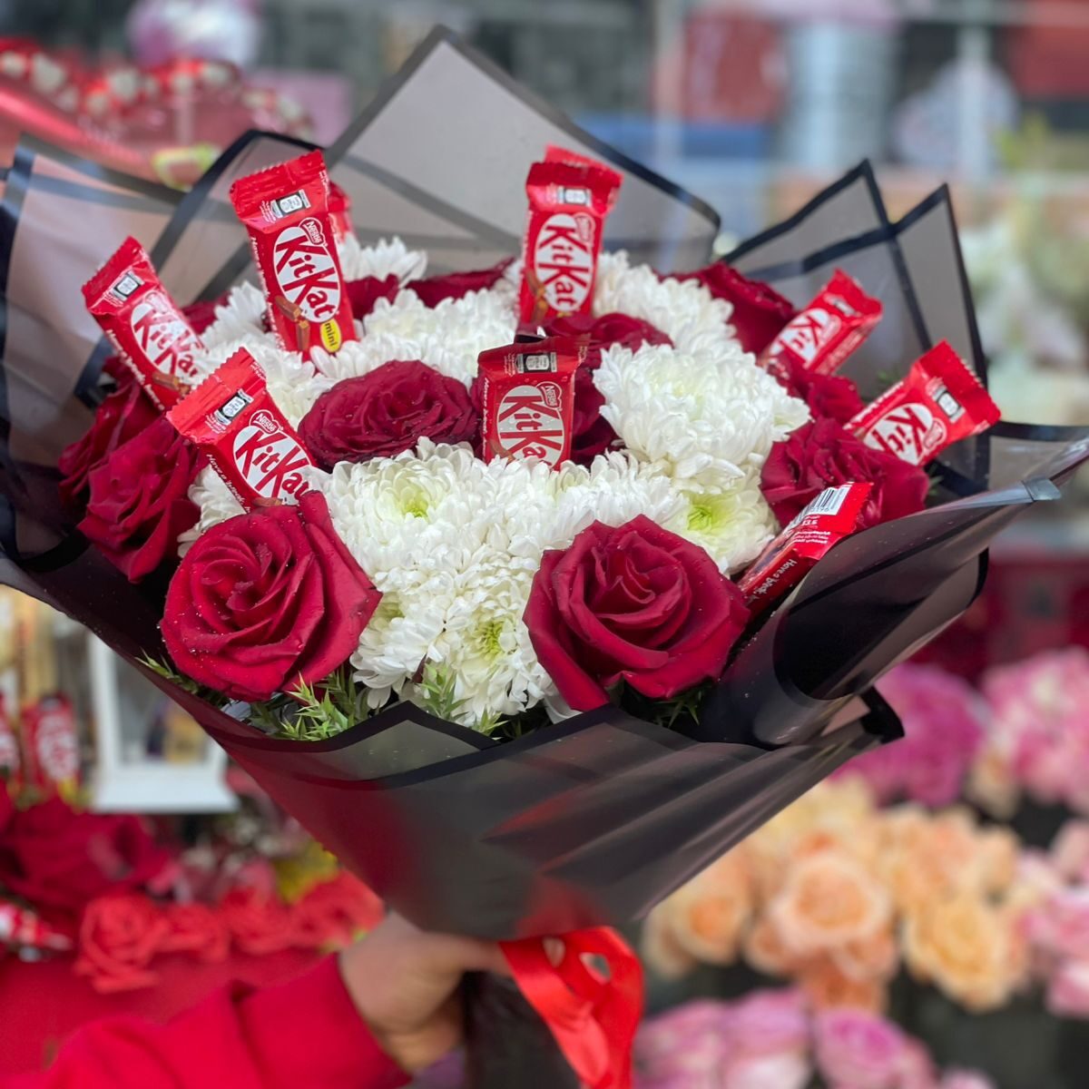 Bouquet of natural red roses, white chrysanthemums, and KitKat chocolates